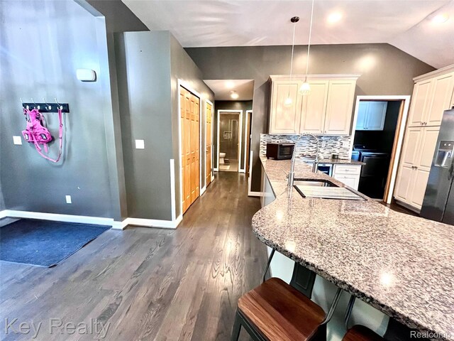 7949 Church Rd, Grosse Ile, MI 48138 - kitchen with light stone countertops, dark wood-style flooring, decorative backsplash, a kitchen breakfast bar, and stainless steel refrigerator with ice dispenser