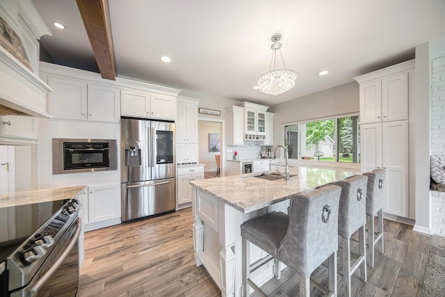 828 Russmiller Loop, Brooklyn, MI 49230 - kitchen with appliances with stainless steel finishes, light stone countertops, light wood-style flooring, white cabinetry, and a chandelier