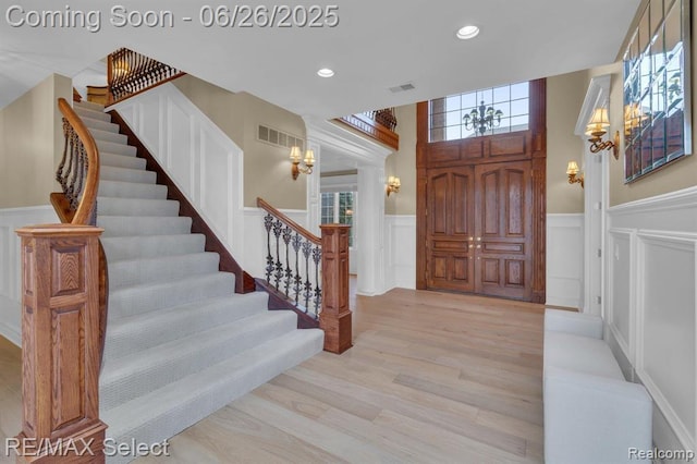 13229 Enid Blvd, Fenton, MI 48430 - foyer entrance with a decorative wall, a chandelier, stairway, a wainscoted wall, and light wood-style floors
