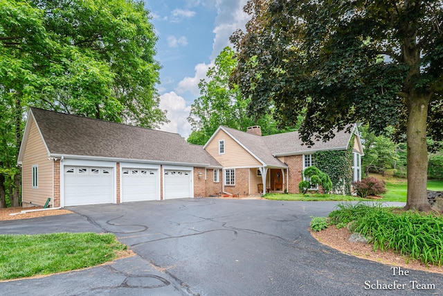 175 Honey Creek Ave NE, Ada, MI 49301 - view of front of home featuring an attached garage, driveway, brick siding, a chimney, and a shingled roof