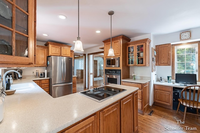 175 Honey Creek Ave NE, Ada, MI 49301 - kitchen with stainless steel appliances, brown cabinetry, light countertops, decorative light fixtures, and light wood-type flooring
