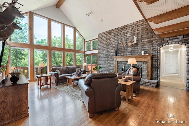 175 Honey Creek Ave NE, Ada, MI 49301 - living area featuring high vaulted ceiling, beam ceiling, arched walkways, hardwood / wood-style flooring, and a brick fireplace