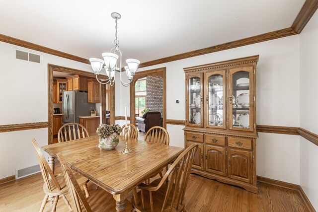 175 Honey Creek Ave NE, Ada, MI 49301 - dining room with a chandelier, light wood-style floors, and ornamental molding