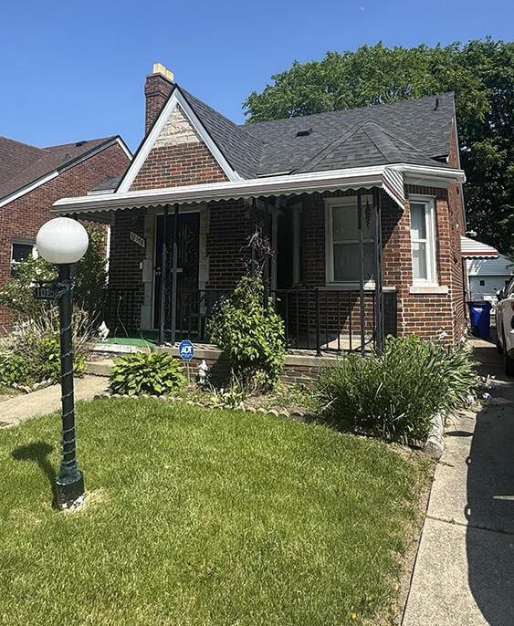 10158 Beaconsfield St, Detroit, MI 48224 - view of front of property with brick siding, covered porch, a front yard, a chimney, and roof with shingles