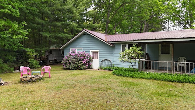 1686 Oak St, Wellston, MI 49689 - view of front of house with an outdoor fire pit, a front yard, and a metal roof