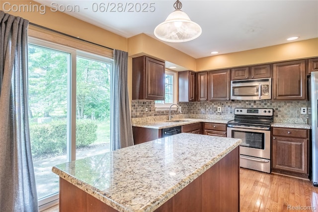 24475 Jamestowne Rd, Novi, MI 48375 - kitchen featuring appliances with stainless steel finishes, backsplash, light wood-type flooring, and light stone countertops