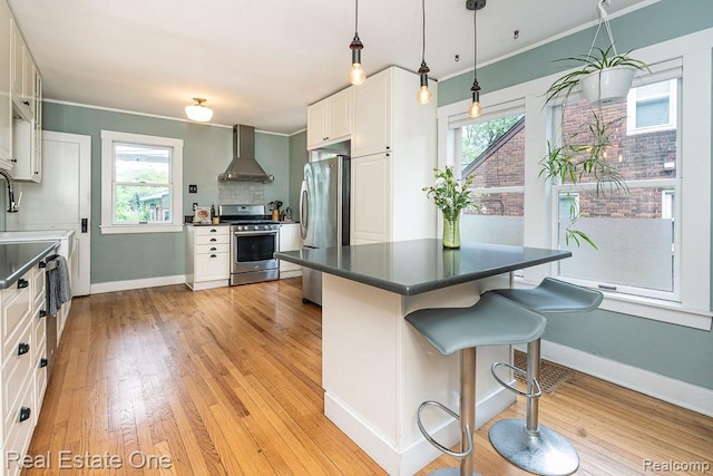 1388 W Troy St, Ferndale, MI 48220 - kitchen with appliances with stainless steel finishes, wall chimney range hood, a breakfast bar area, plenty of natural light, and ornamental molding