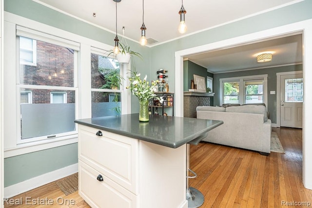 1388 W Troy St, Ferndale, MI 48220 - kitchen featuring ornamental molding, dark countertops, light wood-style floors, white cabinetry, and decorative light fixtures