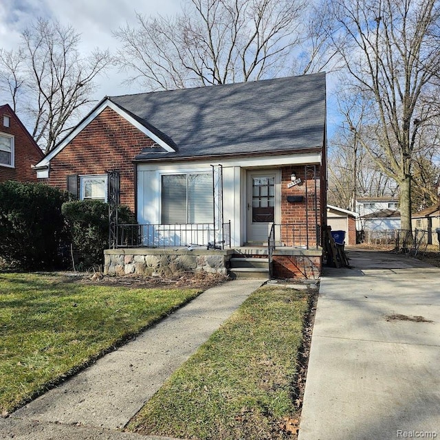 26495 Monticello St, Inkster, MI 48141 - view of front of home featuring brick siding, covered porch, a front yard, roof with shingles, and concrete driveway