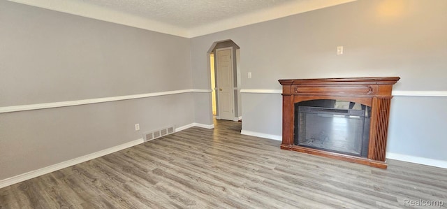 26495 Monticello St, Inkster, MI 48141 - unfurnished living room with wood finished floors, a glass covered fireplace, a textured ceiling, and arched walkways