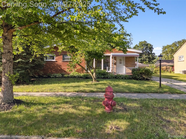 36669 Pinetree St, Livonia, MI 48150 - view of property hidden behind natural elements with a front yard, brick siding, and covered porch