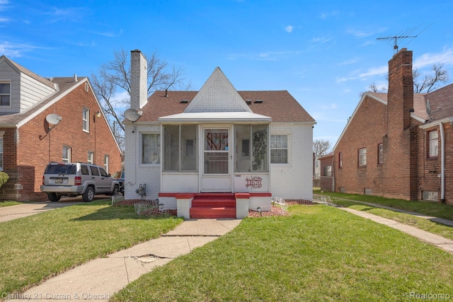 11670 Marlowe St, Detroit, MI 48227 - view of front facade with brick siding, a front lawn, a sunroom, and entry steps