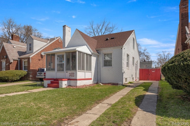 11670 Marlowe St, Detroit, MI 48227 - view of front of house featuring brick siding, a sunroom, and a gate
