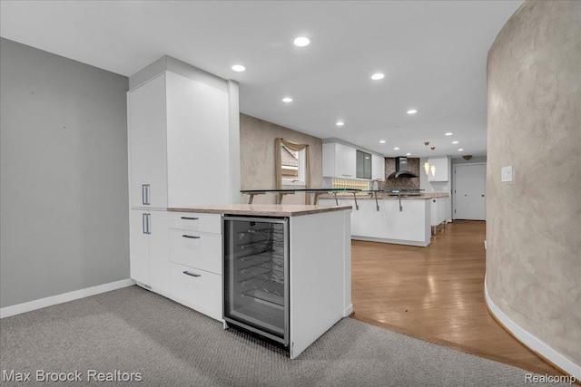 2222 Garland St, Sylvan Lake, MI 48320 - kitchen featuring wine cooler, wall chimney exhaust hood, white cabinetry, recessed lighting, and a peninsula