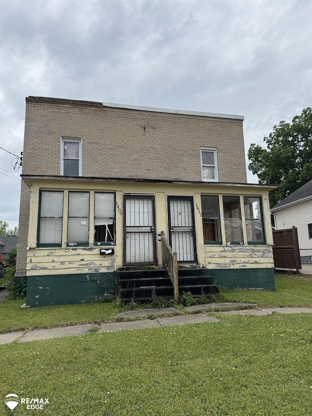 1409 2nd St, Flint, MI 48503 - view of property featuring a front lawn, entry steps, brick siding, and a sunroom
