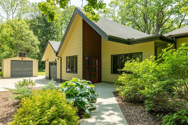 2012 Pontiac Trl, Ann Arbor, MI 48105 - view of front of home featuring a shingled roof, concrete driveway, and an outbuilding