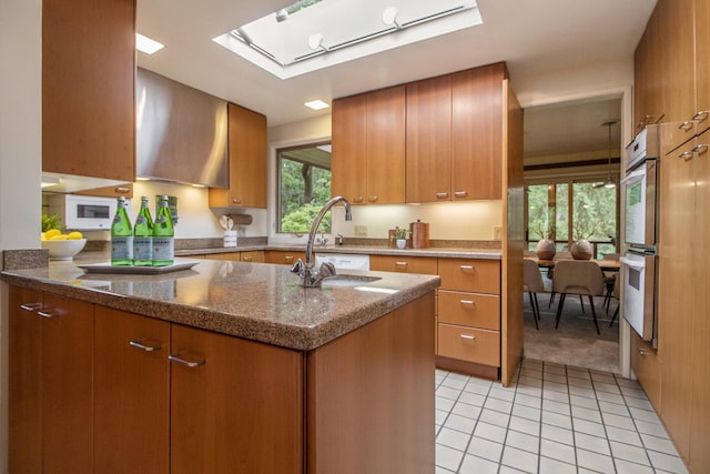13 Regent Dr, Ann Arbor, MI 48104 - kitchen featuring brown cabinetry, a skylight, dark stone countertops, and light tile patterned flooring