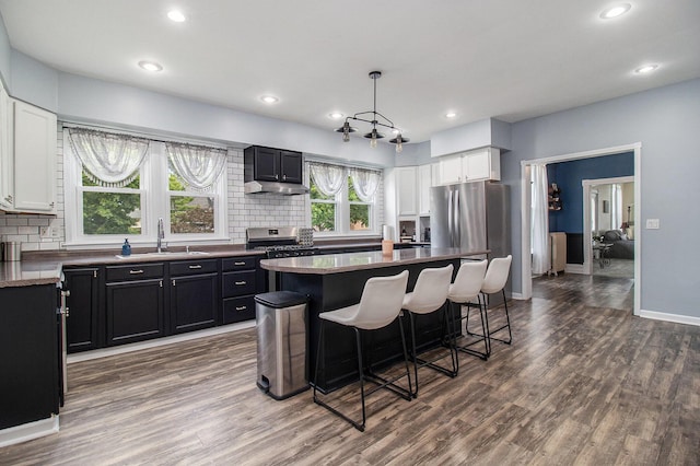 409 E Filer St, Ludington, MI 49431 - kitchen with dark cabinetry, a kitchen bar, backsplash, dark wood finished floors, and recessed lighting