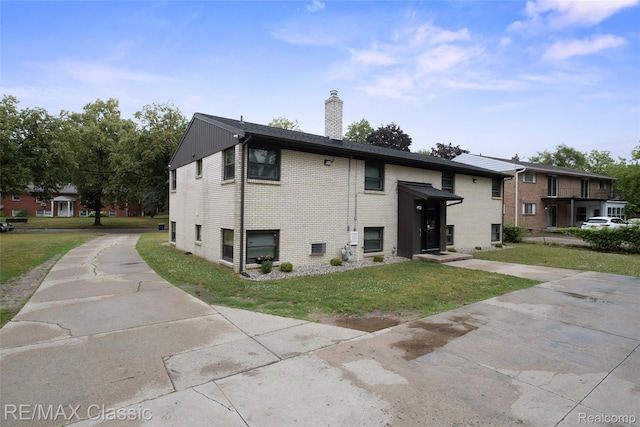 3241MARSHALLAVENUE 3241 Marshall Ave SE, Kentwood, MI 49508 - rear view of property with a chimney, a lawn, brick siding, and concrete driveway