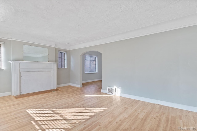14903 Tracey St, Detroit, MI 48227 - unfurnished living room featuring arched walkways, a textured ceiling, light wood-style flooring, and ornamental molding