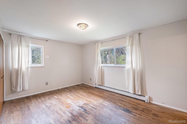 720 E Grand Blanc Rd, Grand Blanc, MI 48439 - empty room featuring a baseboard heating unit, healthy amount of natural light, and wood finished floors