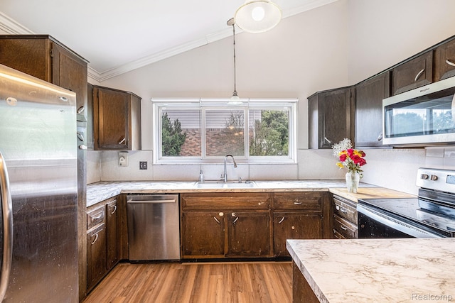 720 E Grand Blanc Rd, Grand Blanc, MI 48439 - kitchen with stainless steel appliances, ornamental molding, lofted ceiling, dark brown cabinetry, and light wood finished floors