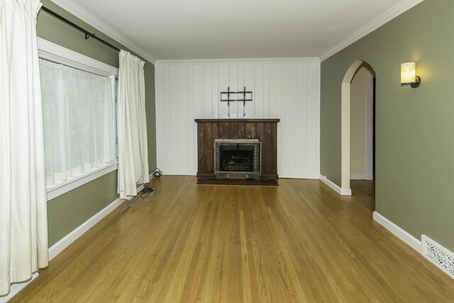 907 Pearl St, Ypsilanti, MI 48197 - unfurnished living room featuring arched walkways, ornamental molding, wood finished floors, and a fireplace with raised hearth