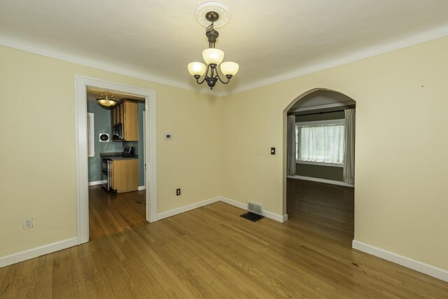 907 Pearl St, Ypsilanti, MI 48197 - unfurnished room with arched walkways, wood finished floors, and a chandelier