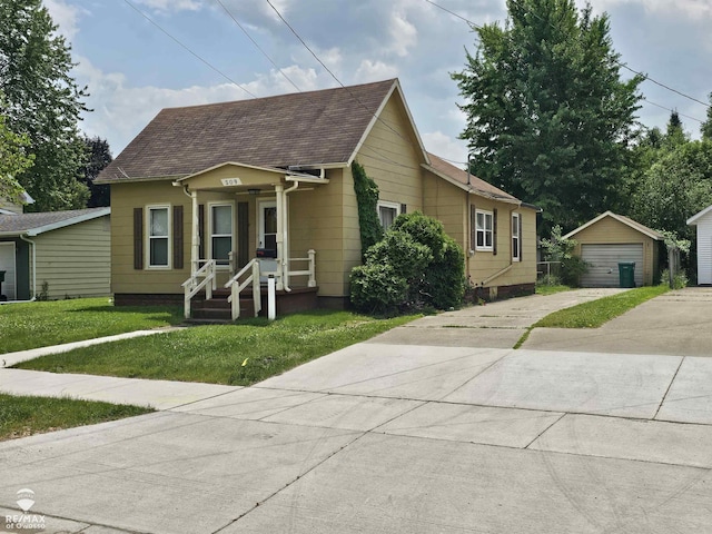 209 W Stewart St, Owosso, MI 48867 - bungalow-style house featuring an outbuilding, a front lawn, a detached garage, roof with shingles, and driveway