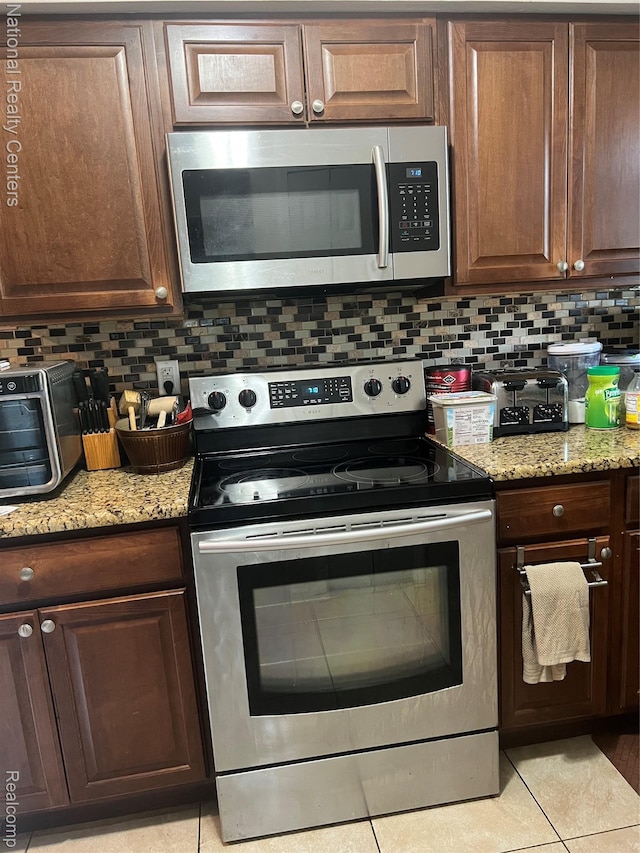 20120 N Covington Pkwy, Southfield, MI 48221 - kitchen with appliances with stainless steel finishes, decorative backsplash, light tile patterned floors, and light stone counters