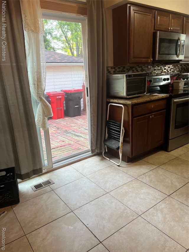 20120 N Covington Pkwy, Southfield, MI 48221 - kitchen featuring appliances with stainless steel finishes, backsplash, light tile patterned floors, and dark countertops