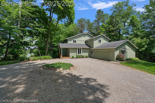 7340 Deer Lake Rd, Clarkston, MI 48346 - view of front facade featuring dirt driveway, a porch, a garage, view of scattered trees, and a shingled roof
