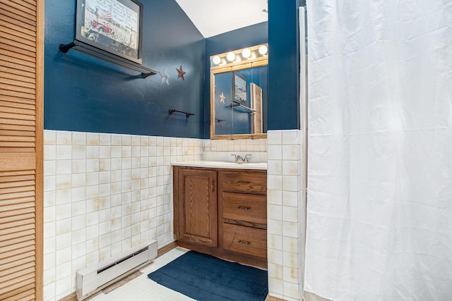 8150 B Dr N, Battle Creek, MI 49014 - bathroom with a baseboard radiator, tile walls, vanity, lofted ceiling, and a wainscoted wall