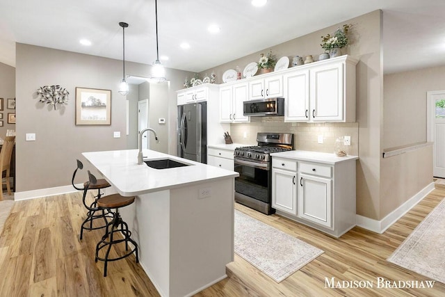 1728 N Brandon Ridge Dr NW, Walker, MI 49544 - kitchen with stainless steel appliances, a kitchen bar, an island with sink, decorative backsplash, and light wood-style flooring