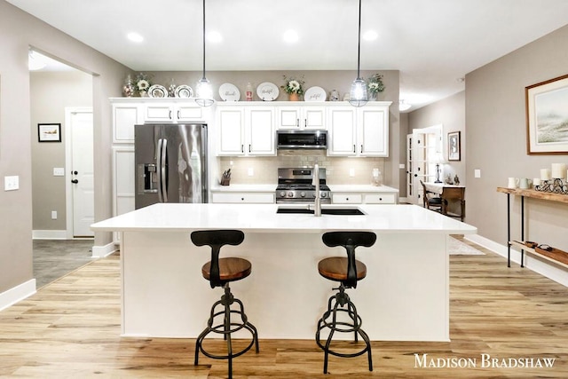 1728 N Brandon Ridge Dr NW, Walker, MI 49544 - kitchen featuring appliances with stainless steel finishes, light wood-style flooring, a kitchen bar, light countertops, and tasteful backsplash