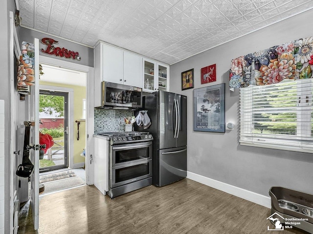 2252 W Temperance Rd, Temperance, MI 48182 - kitchen with stainless steel appliances, an ornate ceiling, white cabinets, wood finished floors, and glass insert cabinets
