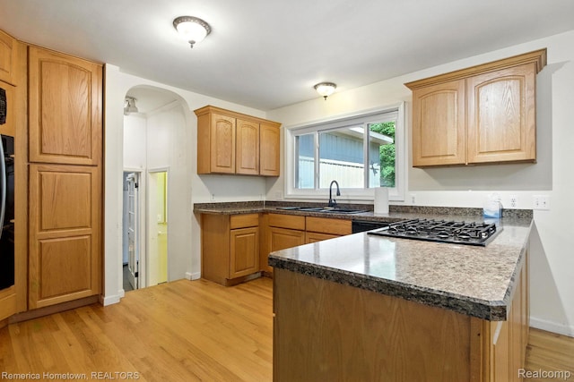 42424 Bradner Ct, Plymouth, MI 48170 - kitchen featuring a peninsula, stainless steel gas cooktop, arched walkways, light wood-style flooring, and dark countertops