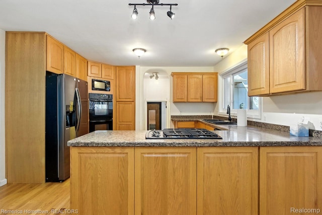 42424 Bradner Ct, Plymouth, MI 48170 - kitchen featuring black appliances, a peninsula, light wood finished floors, and dark stone countertops