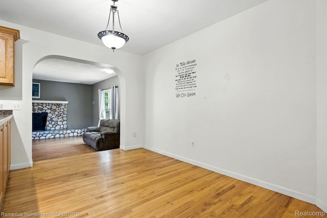 42424 Bradner Ct, Plymouth, MI 48170 - unfurnished room with arched walkways, light wood finished floors, and a fireplace
