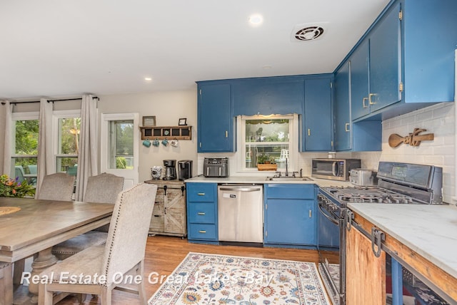 4185 Shattuck Rd, Saginaw, MI 48603 - kitchen with appliances with stainless steel finishes, blue cabinetry, light wood-style floors, backsplash, and recessed lighting