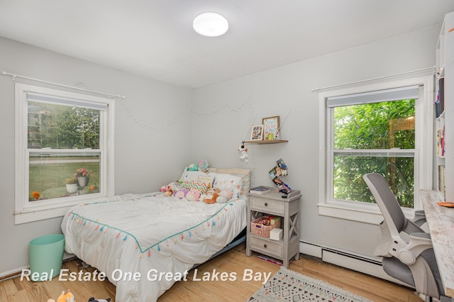 4185 Shattuck Rd, Saginaw, MI 48603 - bedroom with multiple windows, wood finished floors, and a baseboard heating unit