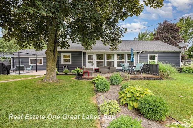 4185 Shattuck Rd, Saginaw, MI 48603 - back of property with a patio area, a lawn, an outdoor living space, and roof with shingles