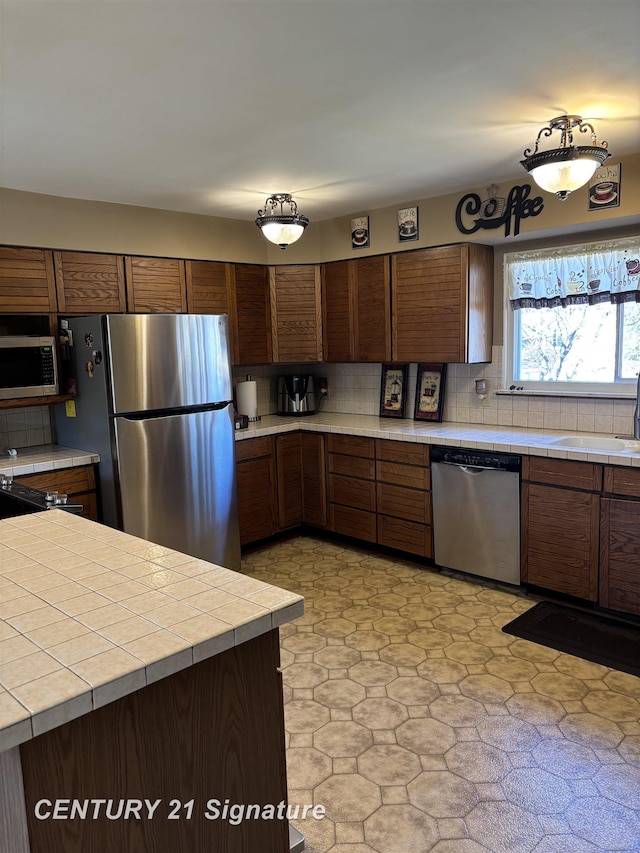 11424 Hazel Ave, Grand Blanc, MI 48439 - kitchen with stainless steel appliances, tile countertops, and decorative backsplash