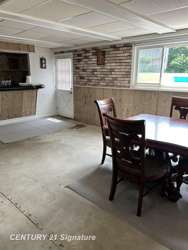 11424 Hazel Ave, Grand Blanc, MI 48439 - dining area with unfinished concrete flooring, wooden walls, and brick wall