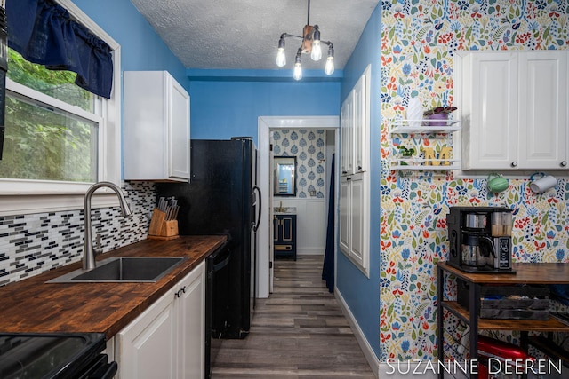 409 W Bridge St, Lyons, MI 48851 - kitchen with butcher block counters, dark wood-style flooring, white cabinetry, decorative backsplash, and black dishwasher