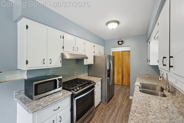 15501 Turner, Lansing, MI 48906 - kitchen with stainless steel appliances, under cabinet range hood, wood finished floors, decorative backsplash, and white cabinetry