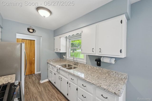 15501 Turner, Lansing, MI 48906 - kitchen with wood finished floors, white cabinetry, black range with gas cooktop, freestanding refrigerator, and light stone countertops