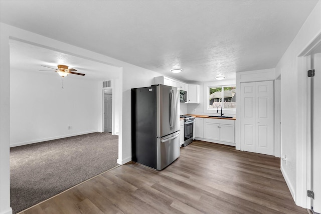 521 E Morrell St, Otsego, MI 49078 - kitchen featuring appliances with stainless steel finishes, white cabinets, dark wood-style floors, ceiling fan, and a textured ceiling