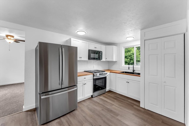 521 E Morrell St, Otsego, MI 49078 - kitchen featuring appliances with stainless steel finishes, wooden counters, white cabinetry, wood finished floors, and a ceiling fan