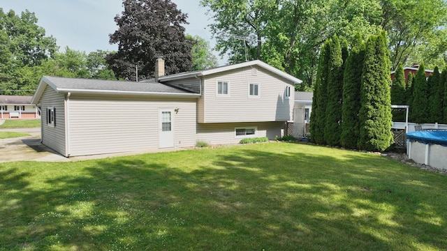 11427 Colonial Woods Dr, Clio, MI 48420 - back of house with a yard, a covered pool, and view of scattered trees